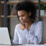 Thoughtful business woman looking at laptop screen