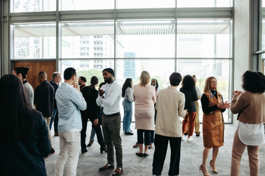 A group of people, professionally dressed, networking in an open room.